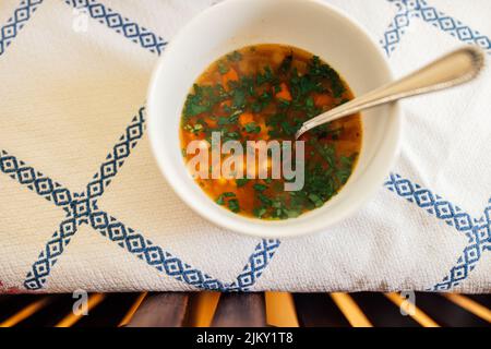 Weiße Bohne, Karotten, italienische Petersiliensuppe in weißer Schüssel auf blauem und weißem Tischtuch Stockfoto