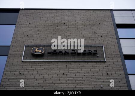 Firmenlogo von John Deere auf einer Backsteinwand des Bürogebäudes von Business Garden. Stockfoto