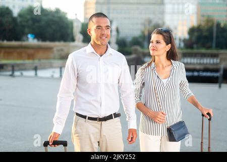 Frauen und Männer, die mit Gepäck durch die Stadt laufen Stockfoto