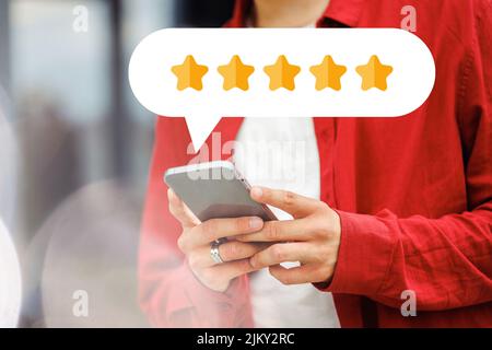 Junge Person mit 5 Sternen auf dem Handy. Stockfoto