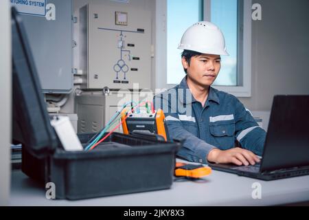 Der Techniker lädt die Daten aus dem Tool zur Leistungsüberprüfung des Solarpanels herunter, um sie auf einem Computer zu analysieren, damit die Stromerzeugung mit vollem capa betrieben werden kann Stockfoto