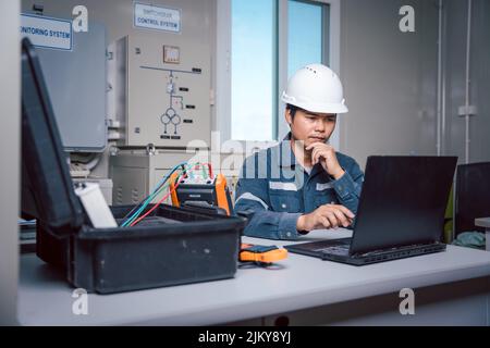 Der Techniker lädt die Daten aus dem Tool zur Leistungsüberprüfung des Solarpanels herunter, um sie auf einem Computer zu analysieren, damit die Stromerzeugung mit vollem capa betrieben werden kann Stockfoto