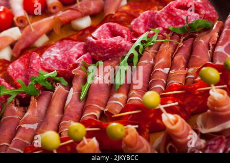 Spanische leckere Mahlzeit Schneiden von Würstchen und Schinken mit Kirschtomaten und Oliven Stockfoto