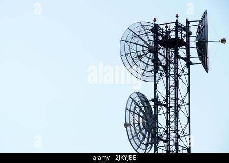 Pylon mit runden Satellitenschüsseln zur Übertragung und Wiederholung von TV-Signalen isoliert auf homogenen Himmel Hintergrund mit Kopierraum Stockfoto