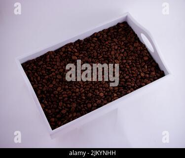 Kaffeebohnen füllen das weiße Holztablett isoliert auf Weiß Stockfoto