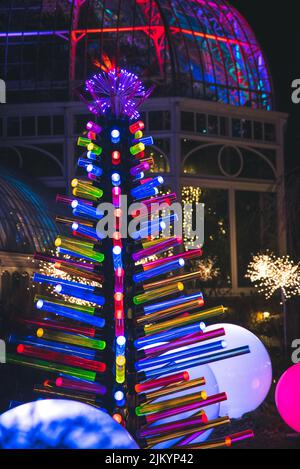 Eine vertikale Aufnahme eines dekorativen Weihnachtsbaums mit bunten Ornamenten als Zweige bei Nacht Stockfoto