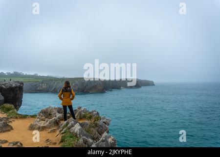 Ein junger Tourist, der die Narren von Pria in der Stadt Llanes betrachtet. Asturien. Spanien Stockfoto
