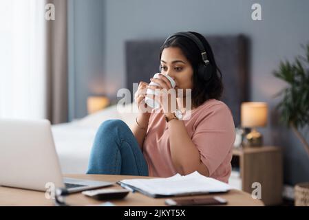 Zeit für eine Kaffeepause. Eine junge Frau, die von zu Hause aus arbeitet. Stockfoto