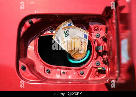 Zwei 50-Euro-Banknoten ragen aus einem Autotank, hohe Transportkosten aufgrund steigender Kraftstoffpreise. Stockfoto