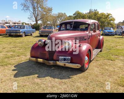 Chascomus, Argentinien - 9. Apr 2022: Alte rote Chevrolet Chevy Master Limousine viertürig 1939 von GM. Grüne Natur Gras und Bäume Hintergrund. Oldtimer-sh Stockfoto