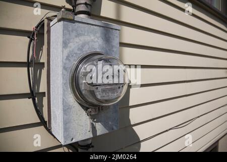 Strom-Messgerät für Wasserkraft an der Außenwand eines Hauses. Stockfoto