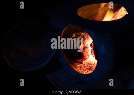 Eine Nahaufnahme von im Feuer brennenden Hölzern flammt im Dunkeln auf einem Ofen Stockfoto