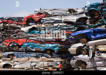 Gestapelte und zerdrückte, weggeworfene Autos auf dem Schrott-Recyclingplatz. Stockfoto