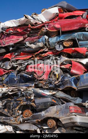 Gestapelte und zerdrückte, weggeworfene Autos auf dem Schrott-Recyclingplatz. Stockfoto