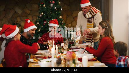 Liebe ist überall in dieser Zeit des Jahres. Eine glückliche Familie, die zu Hause gemeinsam Weihnachtsessen macht. Stockfoto