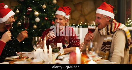 Freundschaft ist unbezahlbarer als jedes Geschenk unter dem Baum. Eine glückliche Gruppe von Freunden, die zu Hause gemeinsam zu Weihnachten essen. Stockfoto