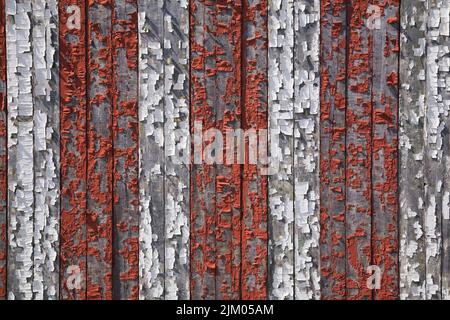 Nahaufnahme der abblätternden roten und weißen Farbe auf dem Holzbrett. Stockfoto