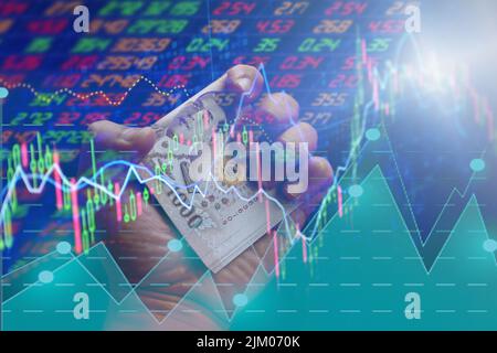 Money Thai 1000 Baht Banknoten in der Hand. Und Aktienchart Trading Exchange Graph. Baht Aufwertung Wechselkurs Konzept. Stockfoto