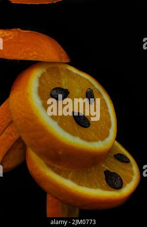Eine vertikale Aufnahme von orangefarbenen Scheiben mit schwarzen Samen auf ihnen Stockfoto