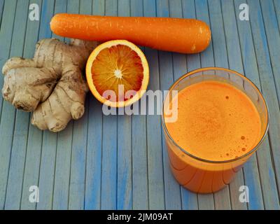 Ein Glas Karotten-, Orangen- und Ingwersaft mit den Zutaten. Blick von oben Stockfoto