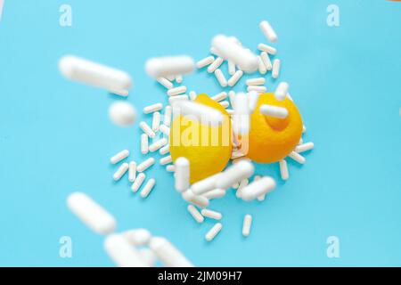 Vitamin C Tabletten.viele Pillen und Zitrusfrüchte. Fliegende Vitamin-C-Pillen und Zitronen auf blauem Hintergrund.natürliches Fruchtvitamin C.Immunitätsmittel Stockfoto