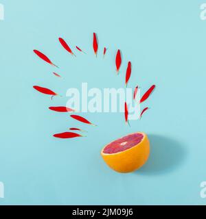 Kreatives Sommer-Layout aus roten orangen und roten Blütenblättern auf hellblauem Hintergrund. Obst minimal Konzept 2 Stockfoto