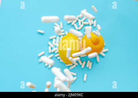 Vitamin C Tabletten.viele Pillen und Zitrusfrüchte. Fliegende weiße Vitamin-C-Pillen und Zitronen auf blauem Hintergrund.natürliches Fruchtvitamin C.Immunität Stockfoto