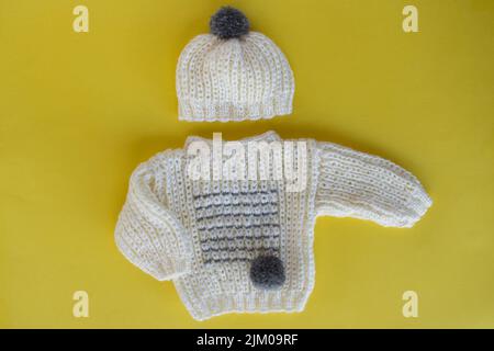 Gestrickter Baby-Pullover und passender Hut mit Pompon Stockfoto