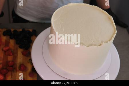 Vor dem Eingeben von Heidelbeeren Erdbeeren zu einem weißen Kuchen backen Stockfoto