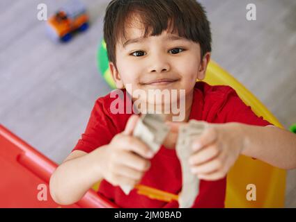 Kleine Jungen machen viel Spaß. Portrait eines entzückenden kleinen Jungen, der zu Hause mit Spielzeug spielt. Stockfoto