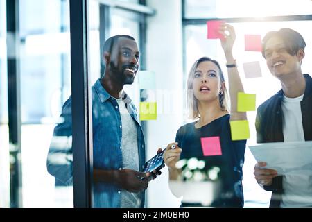 Teamarbeit, Planung und Lesen von Haftnotizen beim Brainstorming, Sprechen oder Ideenaustausch. Eine vielfältige Gruppe kreativer Geschäftsleute, die sich treffen und ausbilden Stockfoto