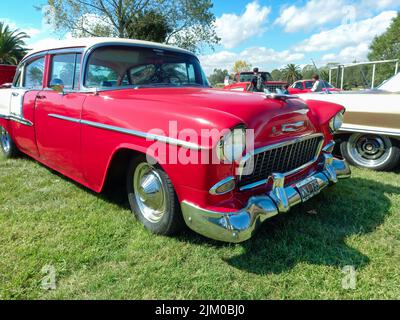 Chascomus, Argentinien - Apr 9, 2022 - Alte rot-weiße Chevrolet Chevy Bel Air Limousine viertürig 1955 geparkt auf dem Gras. Oldtimer-Show. Copyspace Stockfoto