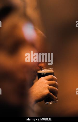 Eine Nahaufnahme einer Hand, die ein Glas Bier hält Stockfoto