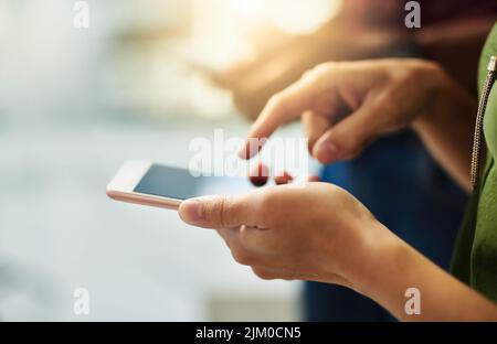Nahaufnahme der Hände eines Geschäftsreisenden, der in einem Büro steht und auf ein Telefon tippt. Draufsicht eines professionellen Scrollens durch Social Media Stockfoto