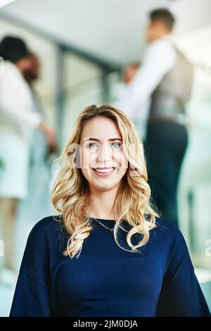 Nahaufnahme Porträt einer glücklichen, fröhlichen und selbstbewussten Geschäftsfrau, die in einem Büro steht. Schöne blonde Frau lächelt und fröhlich mit ihr Stockfoto