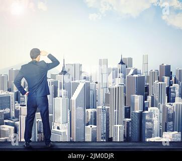 Geschäftsmann, der CGI, digitale und künstliche Gebäude betrachtet, während er von hinten alleine bei der Arbeit steht. Rückseite eines männlichen professionellen Unternehmens Stockfoto