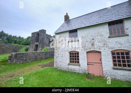 Eines der Arbeiterhäuser, Wohnungen im Vordergrund mit dem Wasserbalance-Turm im Hintergrund. Im Blaenavon Eisenwerk Museum in Blaenavo Stockfoto