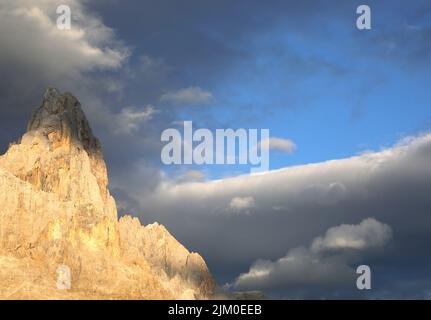 Gipfel des Berges genannt CIMON DELLA PALA in Norditalien mit oranger Farbe bei Sonnenuntergang durch optischen Effekt namens ALPENGLOW und Wolken Stockfoto