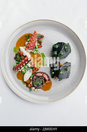 Eine vertikale Draufsicht auf ein Gourmet-Oktopus-Gericht auf weißem Hintergrund Stockfoto