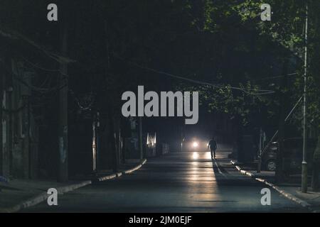 Eine szenische Aufnahme einer asphaltierten Straße in der Nacht und eines Mannes, der dorthin läuft Stockfoto