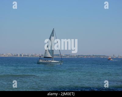 Eine szenische Aufnahme eines weißen Segelbootes im ruhigen Meer unter einem klaren blauen Himmel Stockfoto