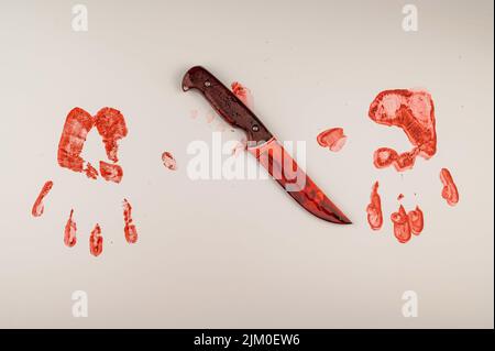 Blutige Messer- und Handdrucke in Blut auf einem weißen Tisch. Stockfoto