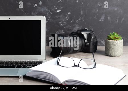 Der Fotograf-Arbeitsplatz mit Kamera, Laptop, Brille auf dem Holztisch Stockfoto