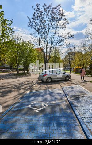 Eine vertikale Aufnahme eines Parkplatzes für behinderte Fahrer und geparktes Auto in Poznan, Polen Stockfoto