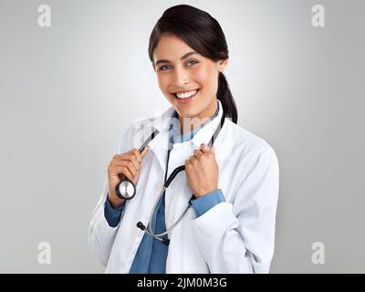 Hat jemand einen Arzt angerufen. Studioportrait eines selbstbewussten jungen Arztes, der vor grauem Hintergrund posiert. Stockfoto