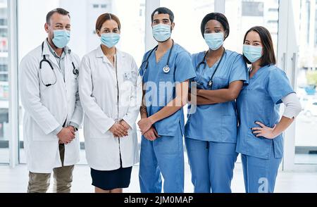 Engagierte Spezialisten stehen bereit, um Ihnen zu helfen. Porträt einer Gruppe von Ärzten, die Gesichtsmasken in einem Krankenhaus tragen. Stockfoto