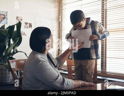 Wow das gehört in ein Museum. Ein entzückender kleiner Junge, der einen Schulauftrag mit seiner Mutter zu Hause abschließt. Stockfoto