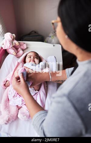 Das Leben wurde gerade viel süßerer. Eine Frau, die zu Hause ihre Babykleidung wechselt. Stockfoto