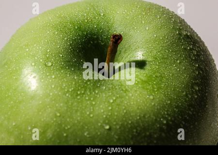 Eine Nahaufnahme eines grünen Apfels mit Wassertropfen Stockfoto