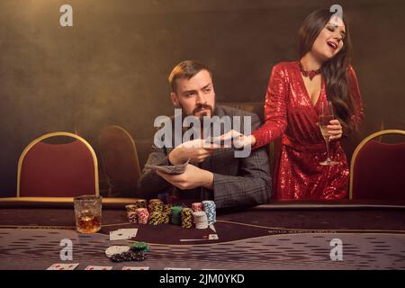 Charmante wohlhabende Paare spielen Poker in einem Casino. Stockfoto